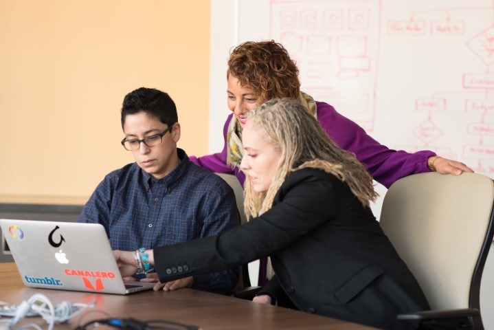 3 colleagues around a laptop