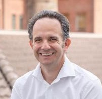 Innovative INCOSE engineering professional smiling outdoors in casual attire.