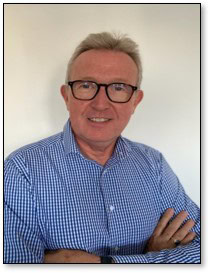 Experienced professional smiling in front of a plain background.