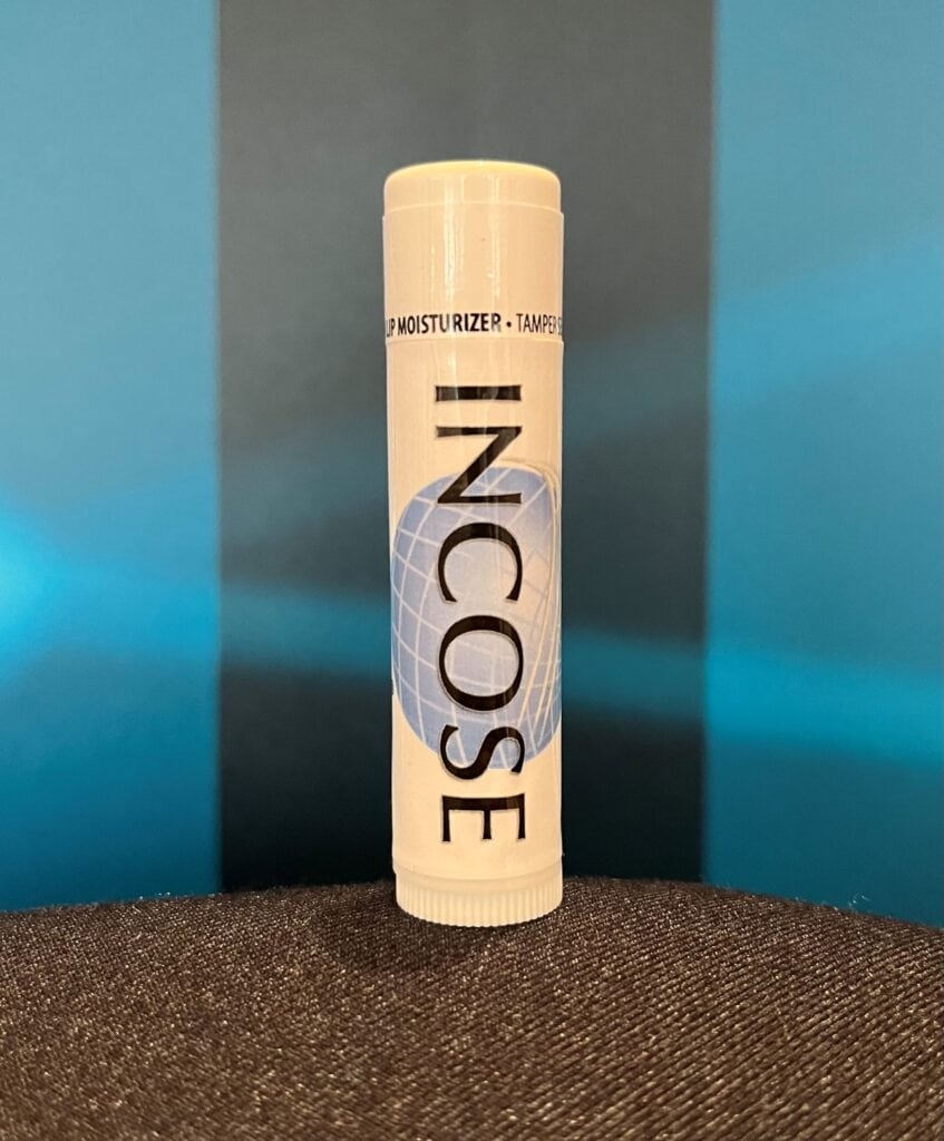 Aloe lip moisturizer stick with IO scent in white tube featuring blue globe design.