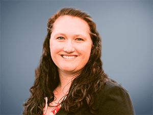 Professional woman smiling, corporate headshot, blue background.