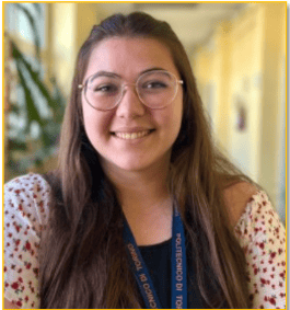 Bright smiling woman with glasses and a blue INCOSE badge at a conference.