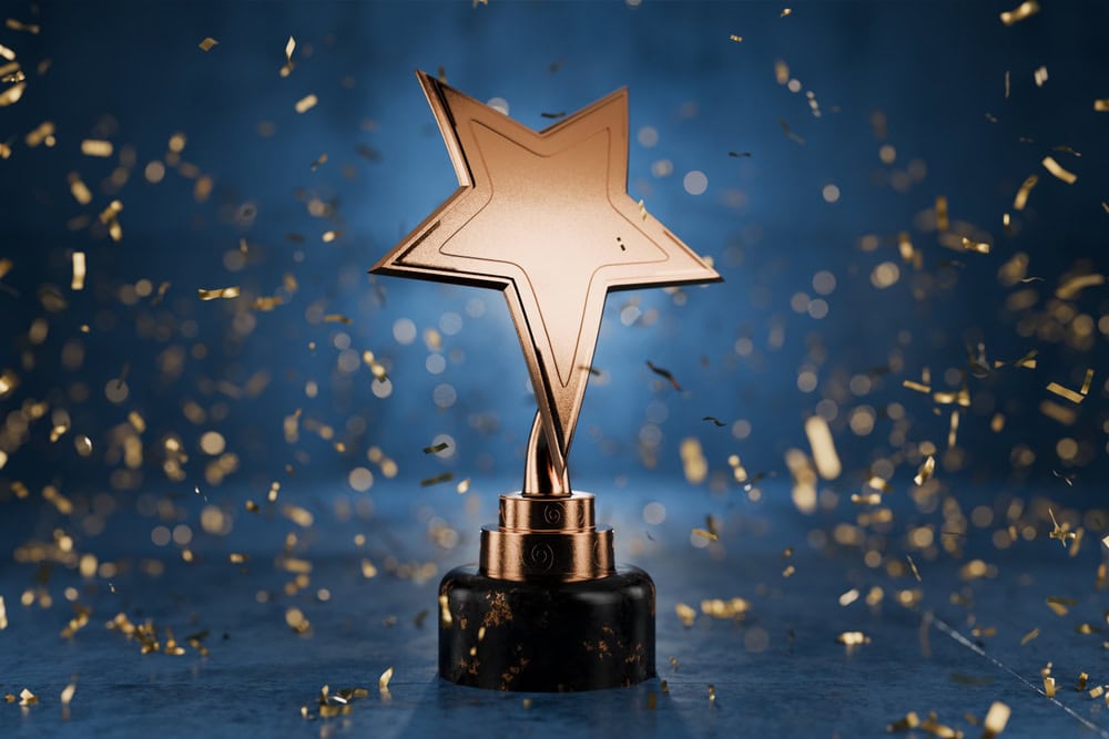 Award trophy with star shape on a black base, surrounded by gold confetti, celebrating achievement.