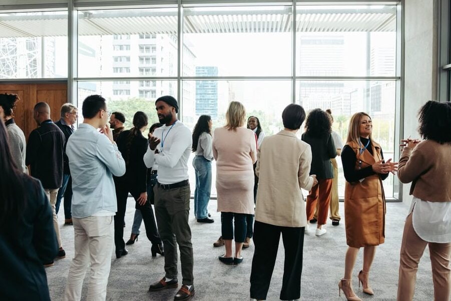 Diverse professionals networking at a modern indoor conference or business event.