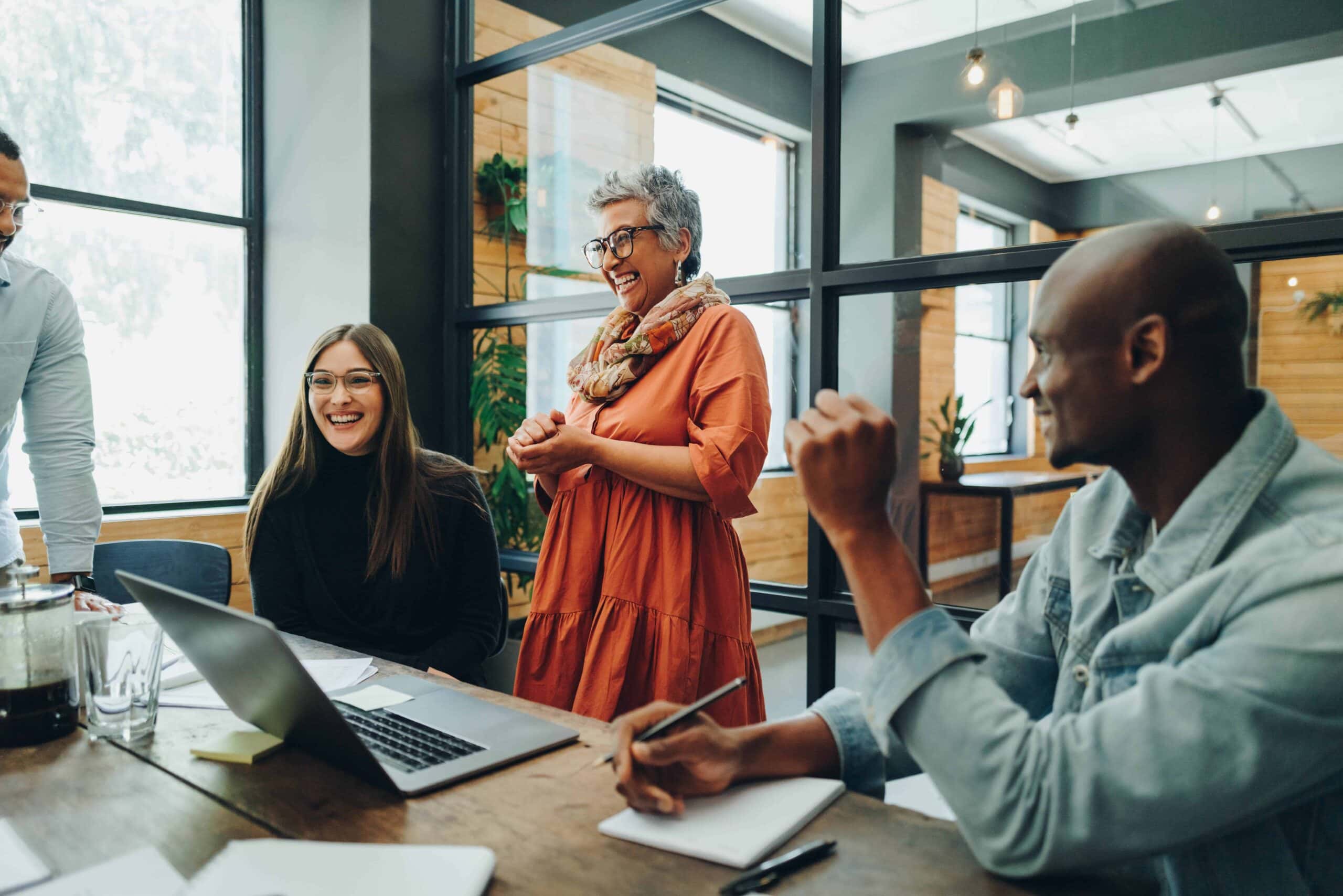 Diverse team collaborating and laughing together in a modern office space.