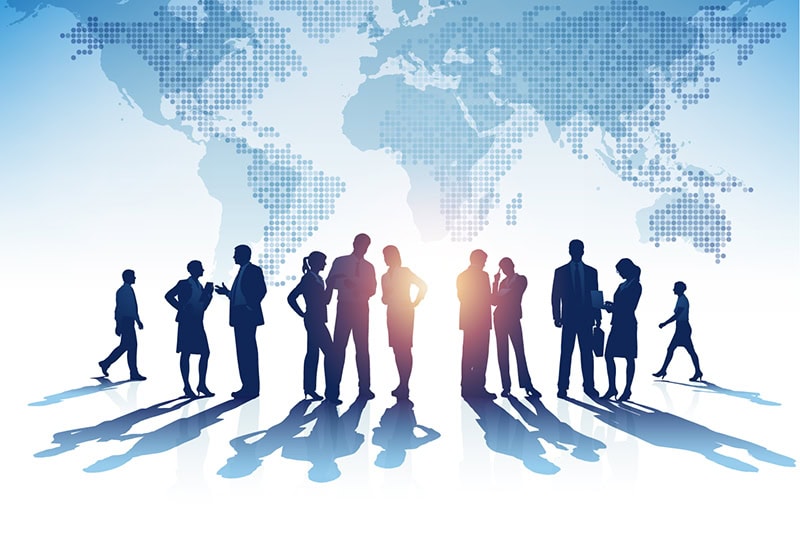Global business team silhouettes with world map background.