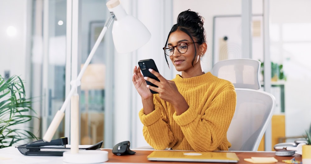Modern woman working in bright office using smartphone.